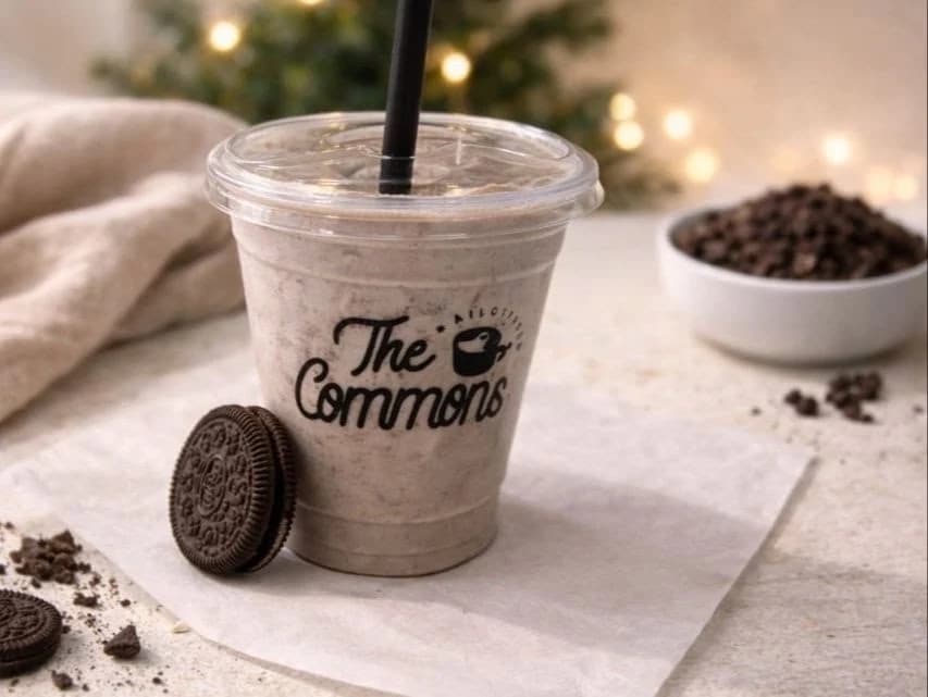 Iced coffee frappe in a The Commons Coffee cup served with an Oreo cookie