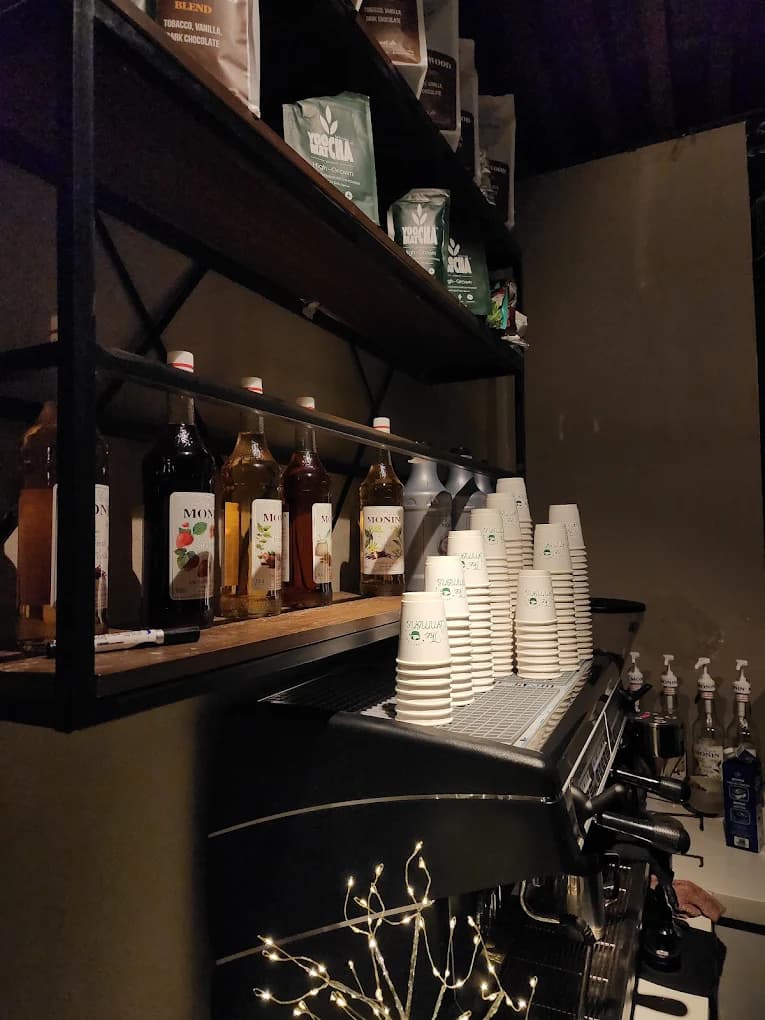 Espresso machine and matcha and syrup bottles behind The Commons Coffee bar